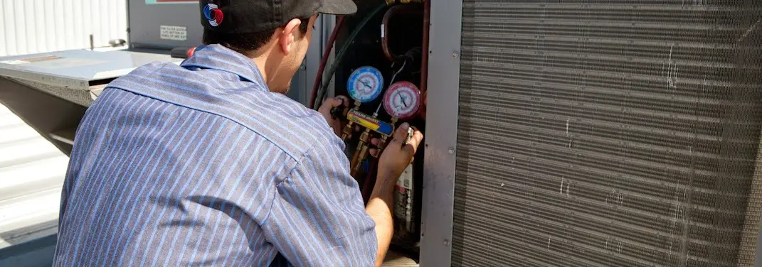 HVAC technician servicing a condenser unit in Littlefield